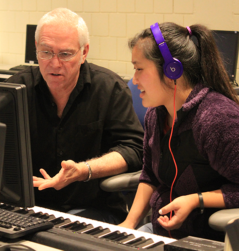 A student receives instruction from a teacher at a music workstation