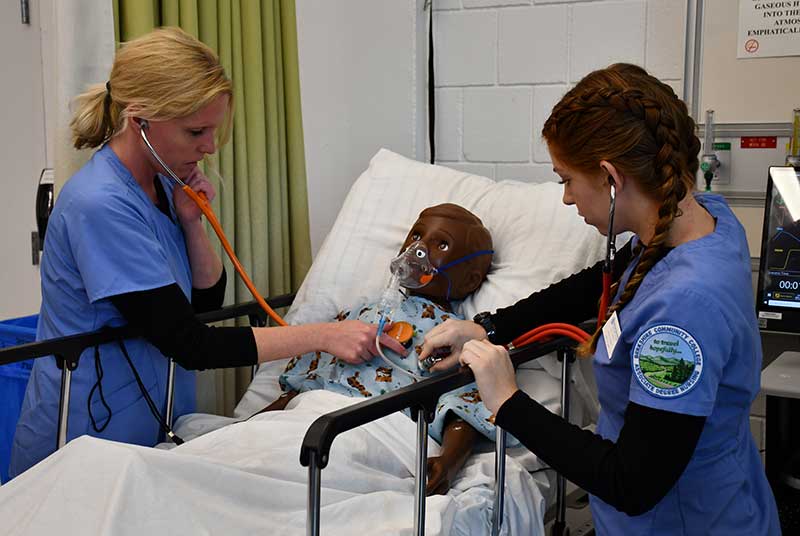 Two nursing students working with a model patient