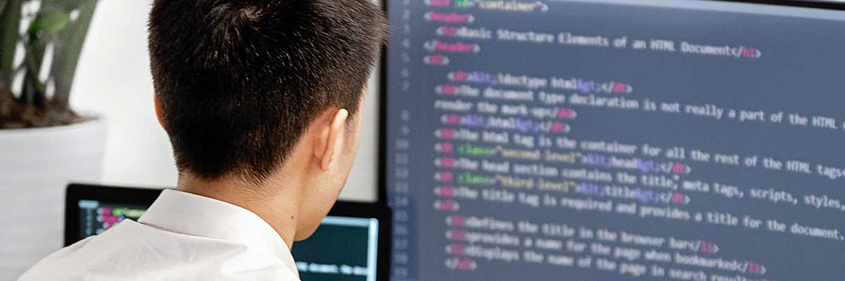 Programming student working at dual monitors